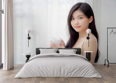 Beautiful young asian sexy woman in underwear drinking coffee near windows in the morning, girl with seductive figure fit drinking beverage for relax and resting after wake up, lifestyle concept. Wall mural