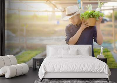 Portrait young asian man walking harvest and picking up fresh organic vegetable garden in basket in the hydroponic farm, agriculture and cultivation for healthy food and business concept. Wall mural