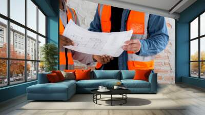 Team of architect or engineer wearing hardhat looking blueprint for inspection and planning construction at construction site, contractor or builder examining and checking project development house. Wall mural