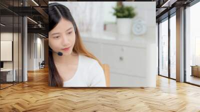 Young asian woman wearing headphone study online with e-learning on desk, girl wearing headset learning to internet with laptop computer at home, new normal, distance education and training. Wall mural