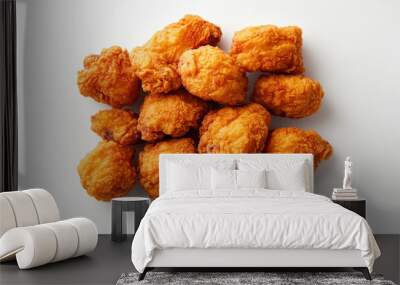 A delicious pile of golden, crispy fried chicken pieces on a white background, enticing and ready to be enjoyed as a tasty meal or snack. Wall mural