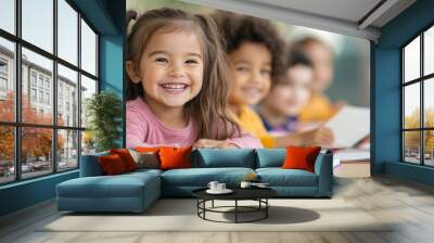 A group of diverse, happy children eagerly sitting at a classroom desk, smiling and holding books, creating a joyful and engaging learning environment. Wall mural