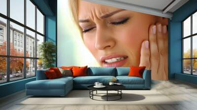 A person appears to be in pain, clutching their cheek with a pained expression, possibly experiencing a toothache or jaw discomfort. Wall mural