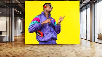 African American young man, in a jacket in the style of the 90s, with a retro cassette player, hears music, the mood of dancing and fun, yellow and purple colors Wall mural