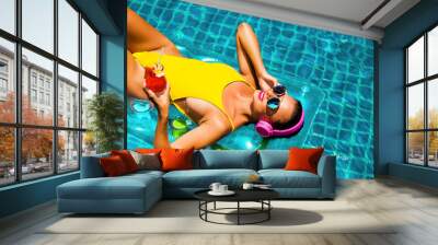 amazing beautiful girl in a yellow bikini air mattress swims in the pool of a luxury hotel, summer vacation, happiness, travel, smile joy, listening to music, drinking cocktail Wall mural