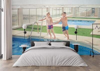 Two boys fun jumping into the swimming pool, shot through the underwater package. Wall mural