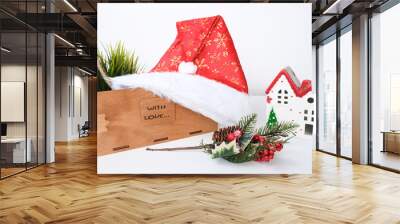 Christmas background with red ceramic decorative house, santa hat and wooden decorations against white Wall mural