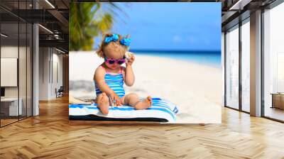 cute little girl listening to shell on beach Wall mural