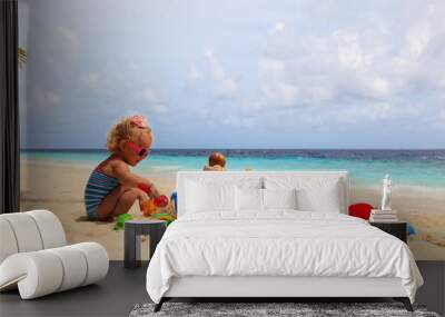 cute little girl playing with sand on beach Wall mural