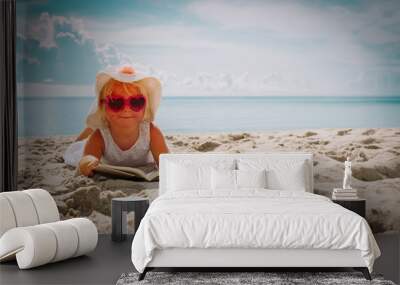 cute little girl reading book at beach Wall mural