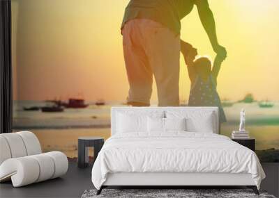 father and little daughter walking on sunset beach Wall mural