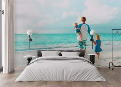 father and two little daughter walk on beach Wall mural