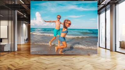 happy little girl and boy run fly play with waves on beach Wall mural