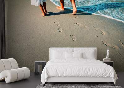 mother and daughter walking on beach leaving footprint in sand Wall mural