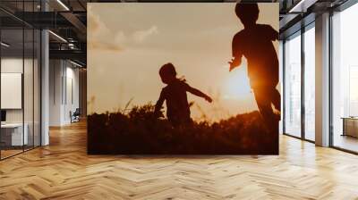 Silhouette of happy boy and girl running at sunset Wall mural