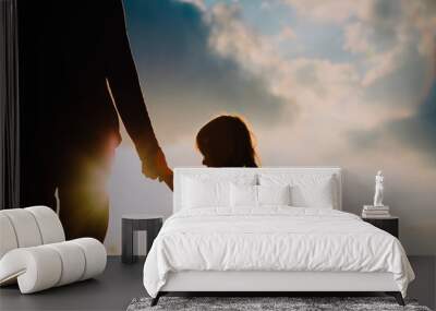 silhouette of little girl holding parent hand at sunset Wall mural