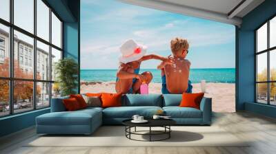 sun protection, little girl applying sunblock cream on boy shoulder Wall mural