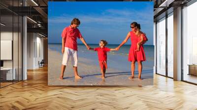 Young family with two kids walking at the beach Wall mural