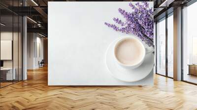   A cup of coffee sits beside a bouquet of lavender on a white tablecloth and white saucer Wall mural