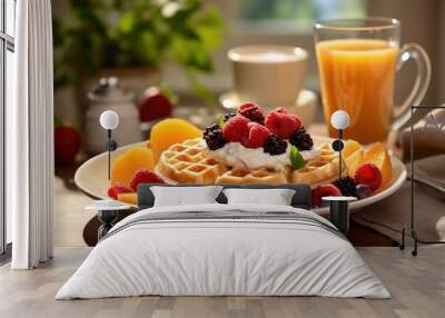  a white plate topped with waffles covered in fruit next to a cup of orange juice and a glass of orange juice. Wall mural