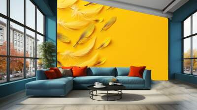  A yellow feather group flies on a yellow background with a feather shadow on the left Wall mural