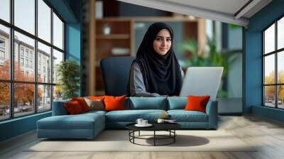 Young arab female employee in traditional outfit working at the table in office Wall mural