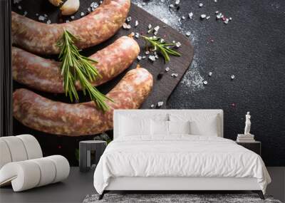 Bratwurst or sausages on cutting board with spices at black table. Wall mural