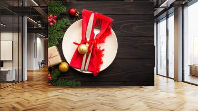 Christmas table setting with craft plate, cutlery, gift box and christmas decorations on dark wooden background. Top view with copy space. Wall mural