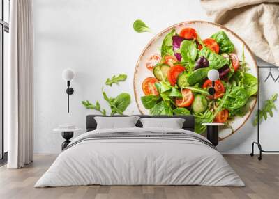 Green salad with fresh leaves and vegetables in white plate. Top view. Wall mural