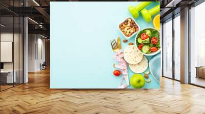 Healthy lifestyle and losing weight background. Sport shoes, dumbell and healthy food on blue. Flat lay with copy space. Wall mural