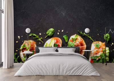 Open sandwiches set with cream cheese, prosciutto, salmon, avocado and fresh greens and vegetables. Top view at dark background with copy space. Wall mural