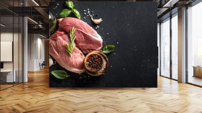 Raw meat steaks with spices, herbs and oil at dark background. Wall mural