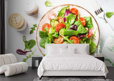 Salad from green leaves and vegetables. Fresh green salad in white plate. Top view. Wall mural