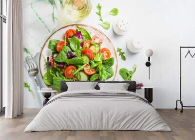 Salad from green leaves and vegetables. Fresh green salad in white plate. Top view. Wall mural