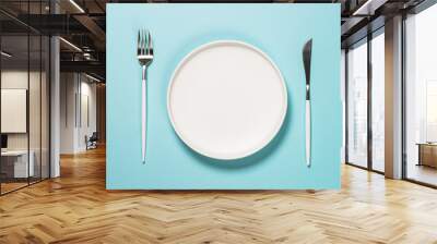 Table setting with white plate and cutlery on blue. Wall mural