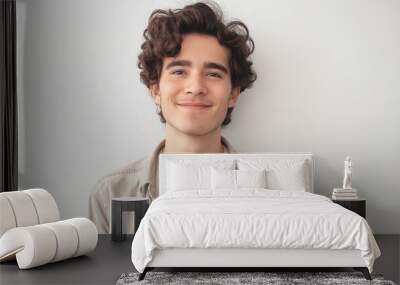 photo of a happy young man with curly hair, wearing casual attire, standing against a white background, smiling and looking at the camera with professional studio lighting Wall mural