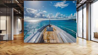 view from the deck of an elegant yacht sailing on clear blue waters with bright sunlight and fluffy clouds above a tropical island Wall mural