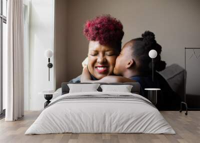 African American girl giving her mother a hug and kiss on cheek Wall mural