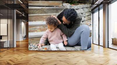 Biracial mom sitting with twins on steps in backyard in fall Wall mural