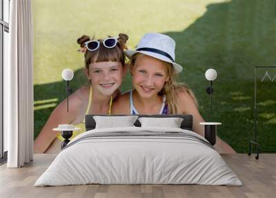 Two girls in swimsuit are having fun on the grass by the pool Wall mural