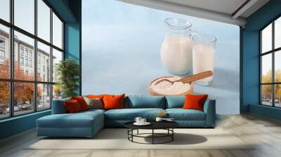 Powdered milk on a blue background and whole milk in a jug and glass Wall mural