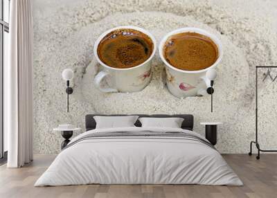 two cups with coffee stand on sand Wall mural