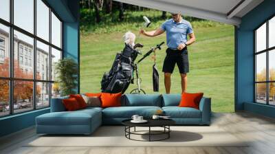 Professional older golfer takes one of clubs out of bag playing outdoors Wall mural