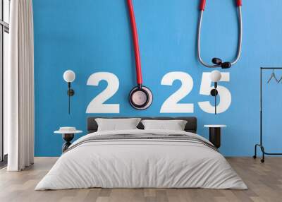 Stethoscope placed beside bold numbers representing the year 2025 on a blue background Wall mural