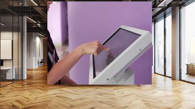 Teenager interacts with touch screen kiosk in purple room Wall mural