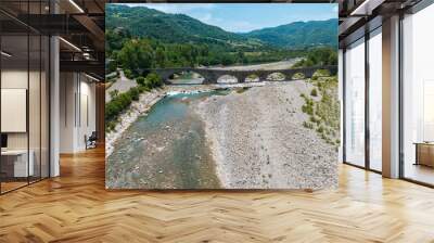 Aerial view. Drought and dry rivers. Roman bridge of Bobbio over the Trebbia river, Piacenza, Emilia-Romagna. Italy. River bed with stones and vegetation. Called hunchback bridge Wall mural