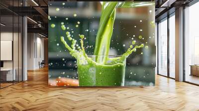 A close-up shot of a fresh, vibrant green smoothie being poured into a glass, with splashes frozen in motion, and a blurred kitchen background. Wall mural