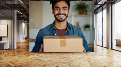 Portrait of a Arabian smiling delivery man holding a large cardboard box. Delivery Arabian man isolated on blue background laughing Wall mural