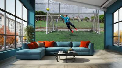 Young Hispanic female goalkeeper trying to catch a ball Wall mural