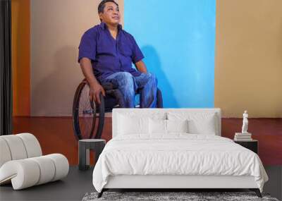 Middle-aged Hispanic man with disabilities on a wheelchair against a colorful background Wall mural